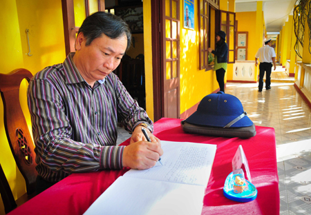 Ông Nguyễn Đắc Tài viết cảm xúc vào sổ lưu niệm của các đảo đoàn đi qua