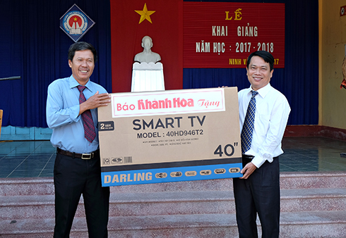 Ông Trần Duy Hưng - Tổng Biên tập Báo Khánh Hòa (bên phải) tặng quà cho trường THCS Nguyễn Phan Vinh