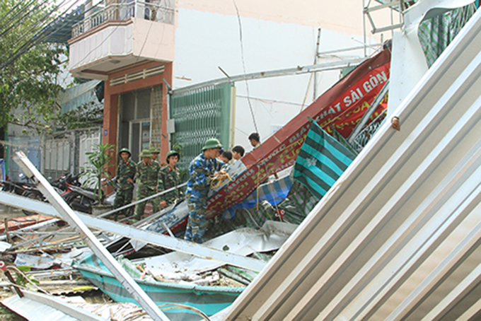 Giáo viên và học viên Trường trung cấp kỹ thuật Miền Trung giúp dân thu dọn mái nhà bị tốc.