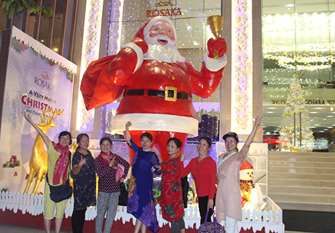 Du khách chụp ảnh lưu niệm với ông già Noel lớn đặt trước khách sạn Rosaka, đường Nguyễn Thiện Thuật. 
