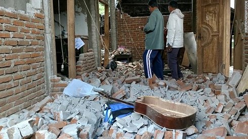 Dân làng đi qua một ngôi nhà bị hư hại sau trận động đất 6,4 độ richter xảy ra tại Lombok vào ngày 29/7. (Ảnh: CNN)