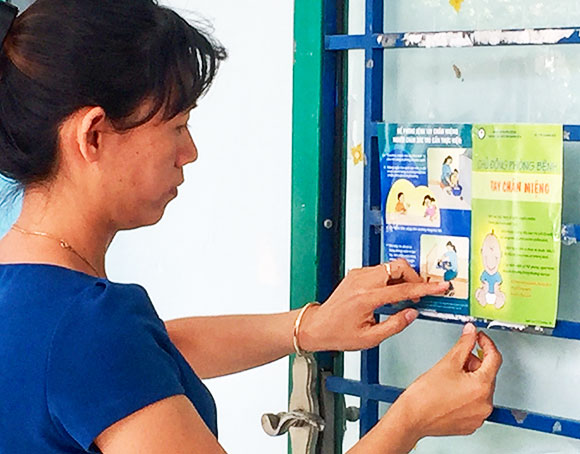 Giáo viên Trường Mầm non Hướng Dương, huyện Cam Lâm dán hướng dẫn phòng bệnh tay chân miệng ở lớp học.