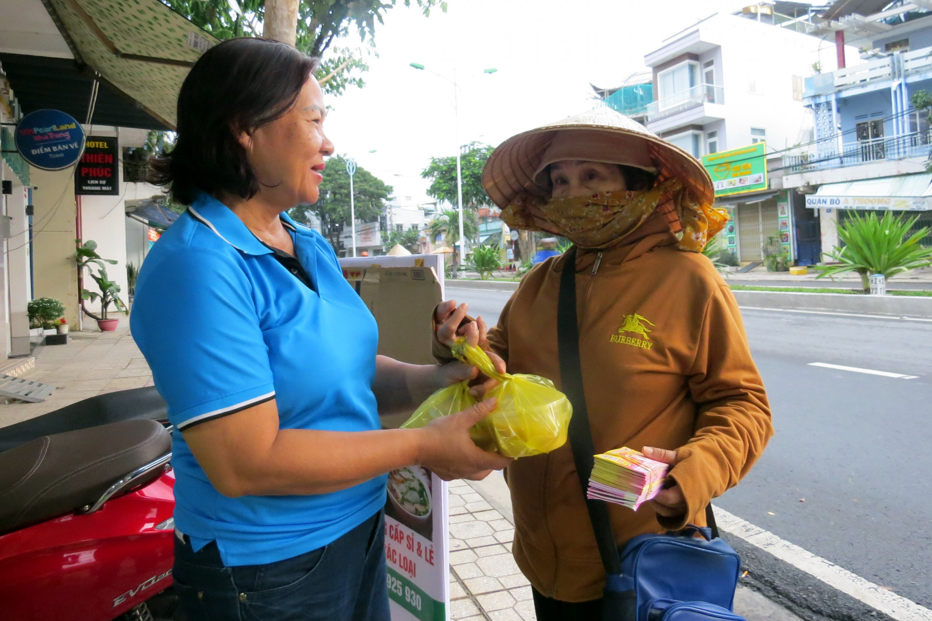 Cán bộ Hội LHPN phường Vĩnh Nguyên phát cháo miễn phí cho người  khó khăn.