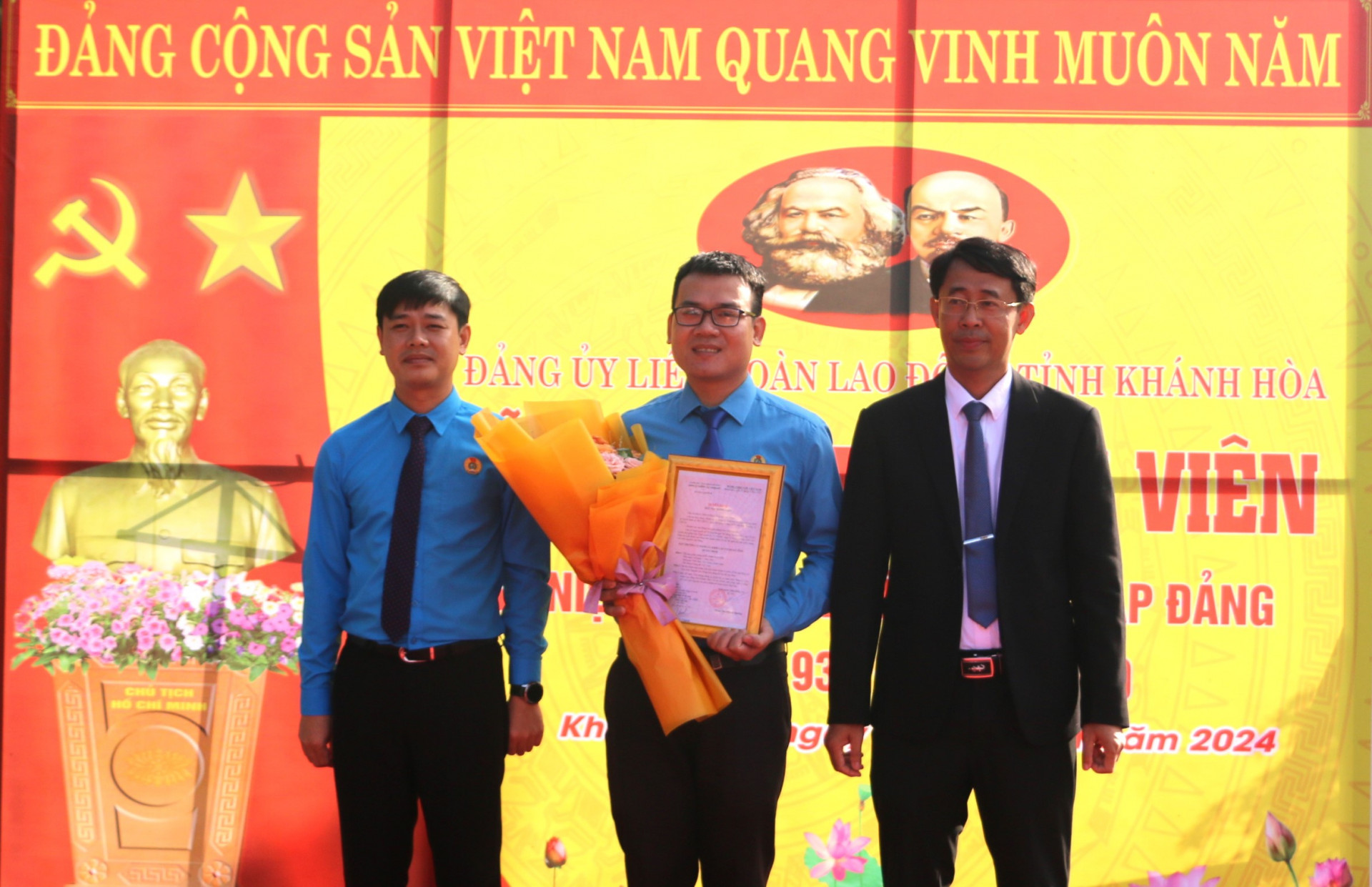 Ông Trịnh Văn Mơ – Phó Bí thư Đảng ủy kiêm Trưởng Ban Tổ chức Đảng ủy Khối các cơ quan tỉnh (bên phải) và ông Bùi Hoài Nam - Bí thư Đảng ủy, Chủ tịch Liên đoàn Lao động tỉnh trao quyết định, tặng hoa chúc mừng đảng viên mới.