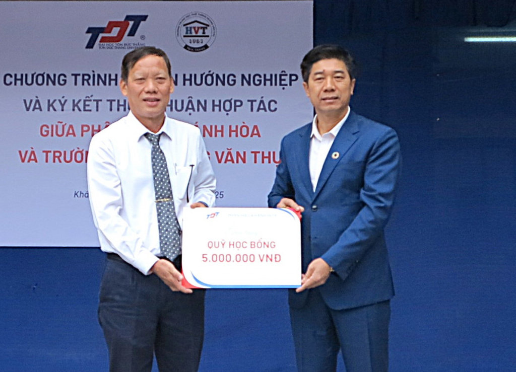 Đại diện Trường Đại học Tôn Đức Thắng Phân hiệu Khánh Hòa (bên phải) trao bảng tượng trưng hỗ trợ học bổng cho Trường THPT Hoàng Văn Thụ.