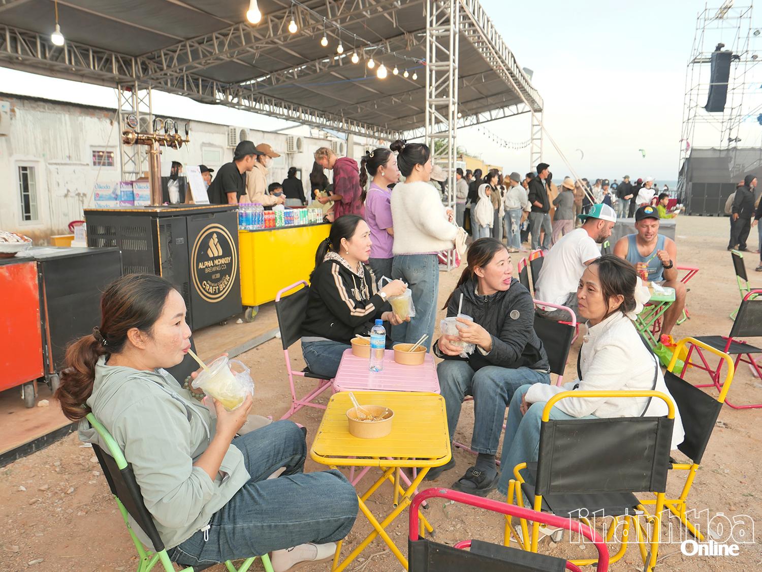 Người dân và du khách nước ngoài thưởng thức các loại thức ăn, đồ uống được bày bán tại các gian hàng ẩm thực.