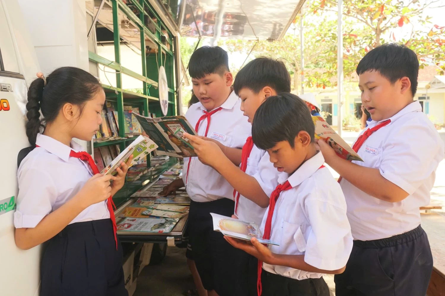 Các em học sinh thích thú đọc sách tại Gian hàng sách lưu động.