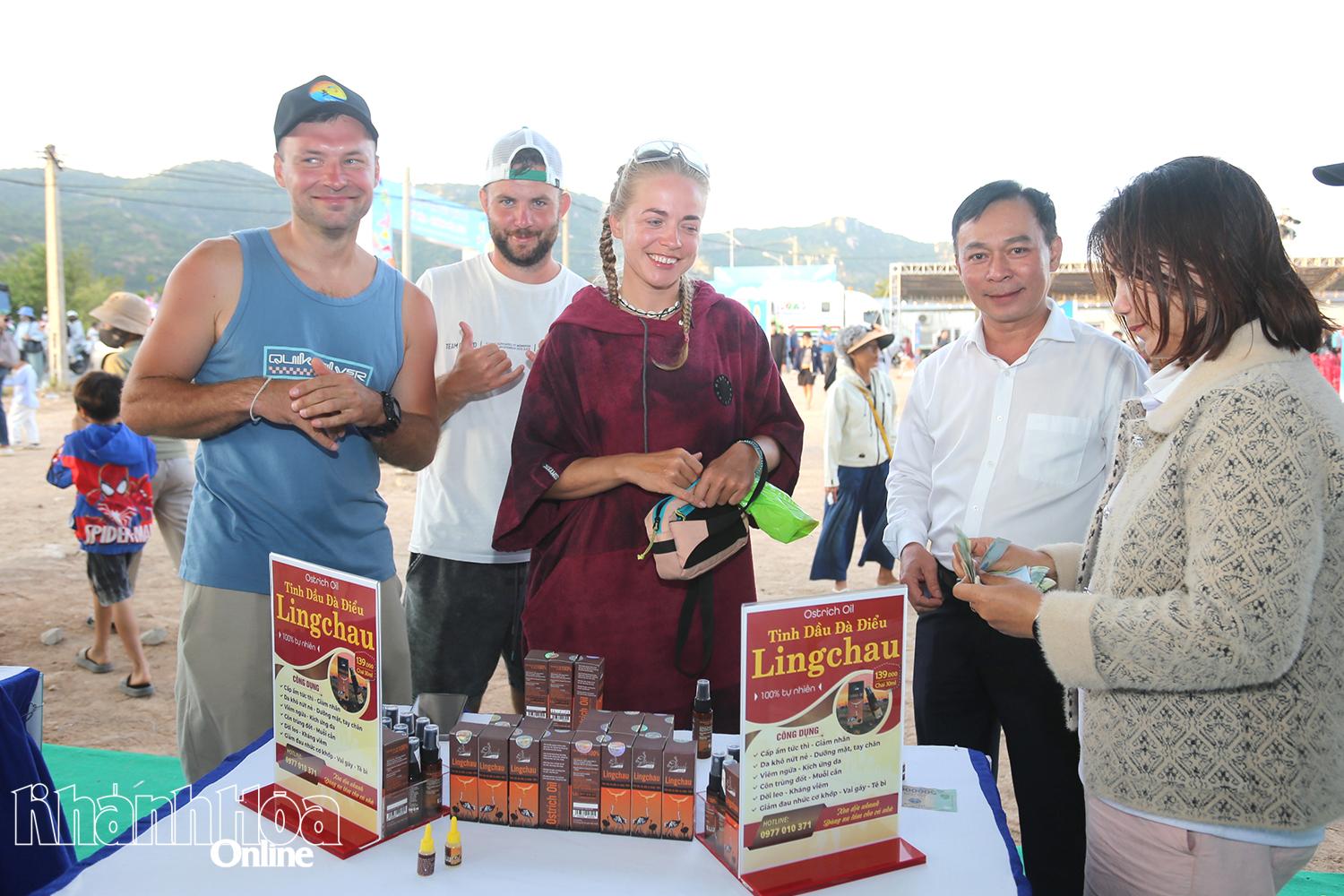 Các du khách nước ngoài xem và mua sản phẩm tinh dầu tại một gian hàng.