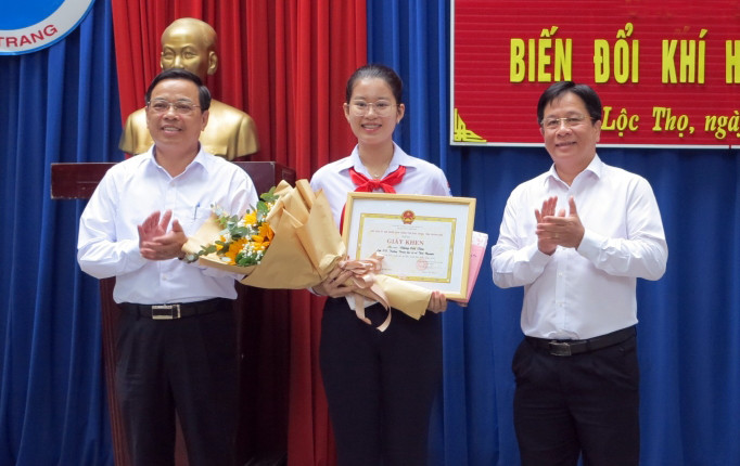 Đồng chí Hồ Văn Mừng (bìa phải) và ông Nguyễn Sỹ Khánh tặng hoa chúc mừng và trao giấy khen cho em Đặng Cát Tiên.
