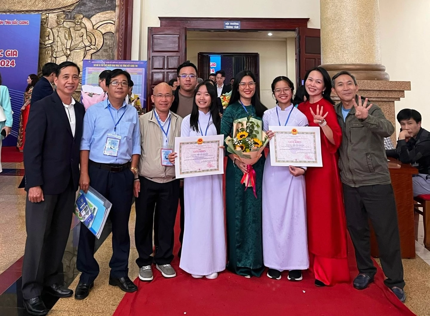 Hai em Nhiên và Thơ chụp ảnh lưu niệm cùng các thầy cô tại Cuộc thi Khoa học kỹ thuật cấp quốc gia năm học 2023-2024.