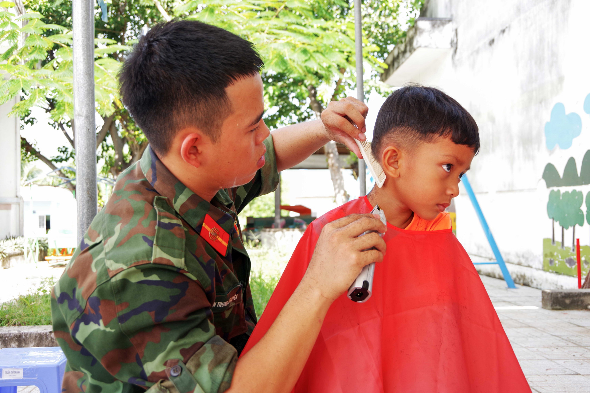 Đoàn viên, thanh niên Trường Sĩ quan Thông tin cắt tóc miễn phí cho trẻ em.