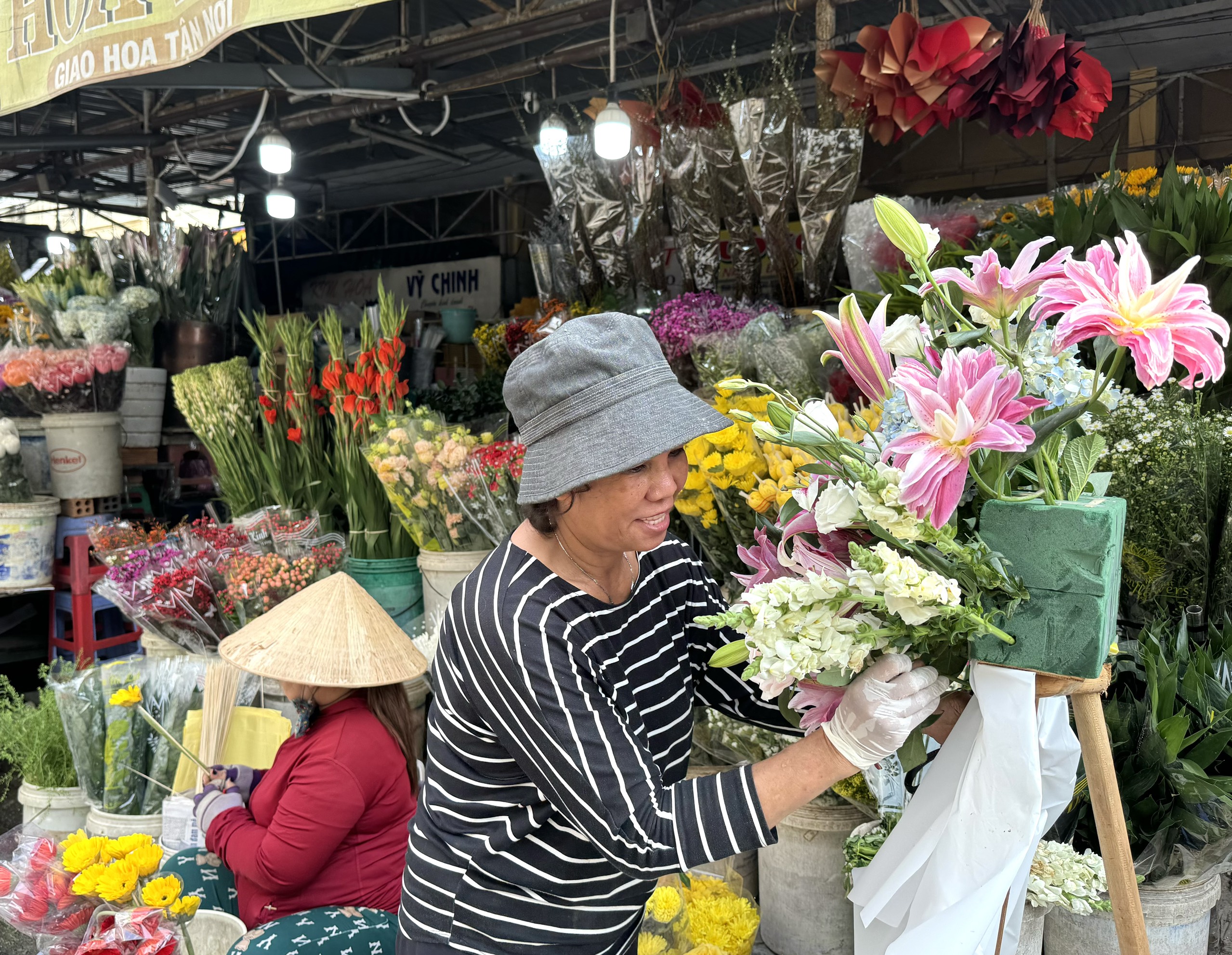 Một tiểu thương bán hoa tại chợ Xóm Mới cắm hoa chuẩn bị giao cho khách