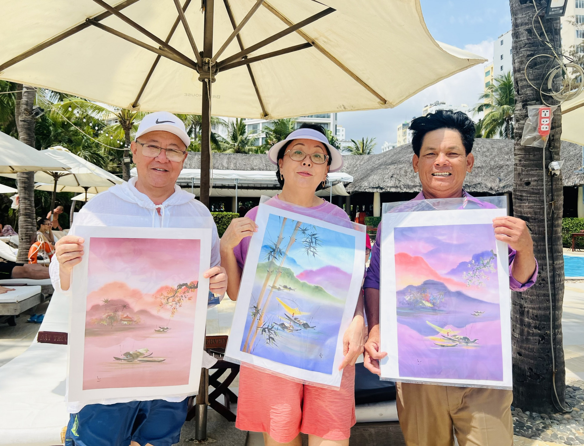 Ông Phạm Minh Hồng (bên phải) cùng 2 du khách đến từ Kazakhstan bên những bức tranh phong cảnh Việt Nam. 