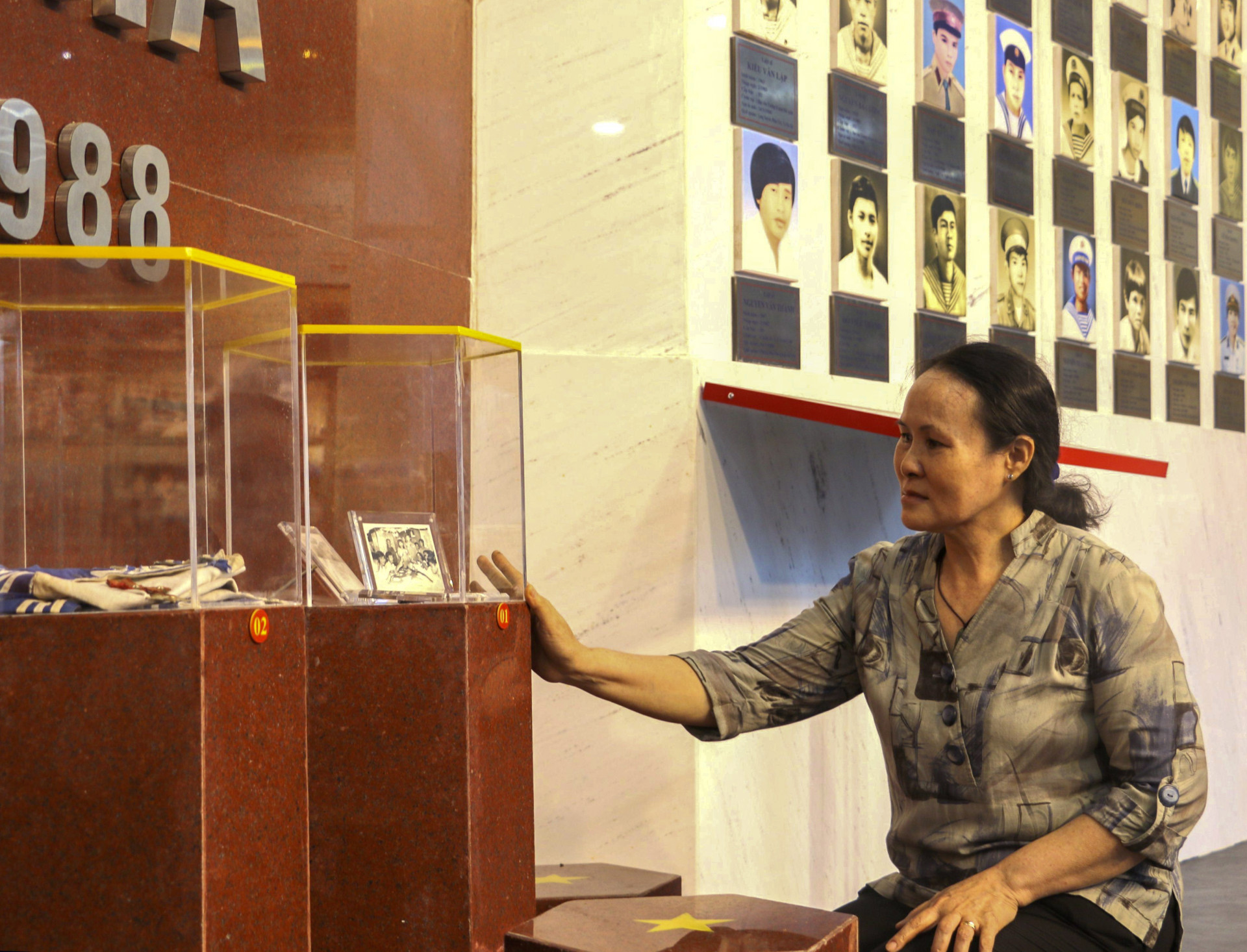 Bà Đỗ Thị Hà bên những bức ảnh chụp ngày cưới 
được bà trao lại cho Khu tưởng niệm chiến sĩ Gạc Ma trưng bày.
