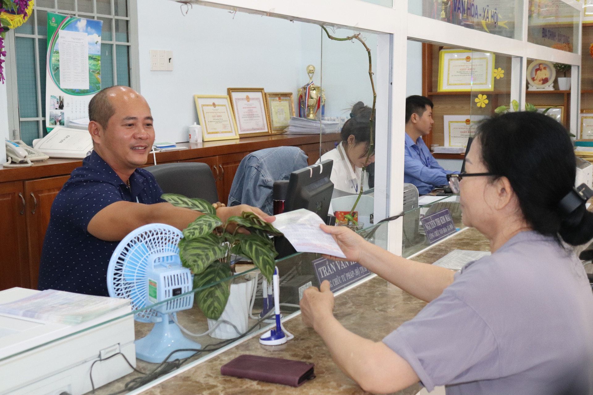 Công chức phường Tân Lập phát tài liệu tuyên truyền Nghị quyết số 18 cho người dân đến làm thủ tục hành chính.