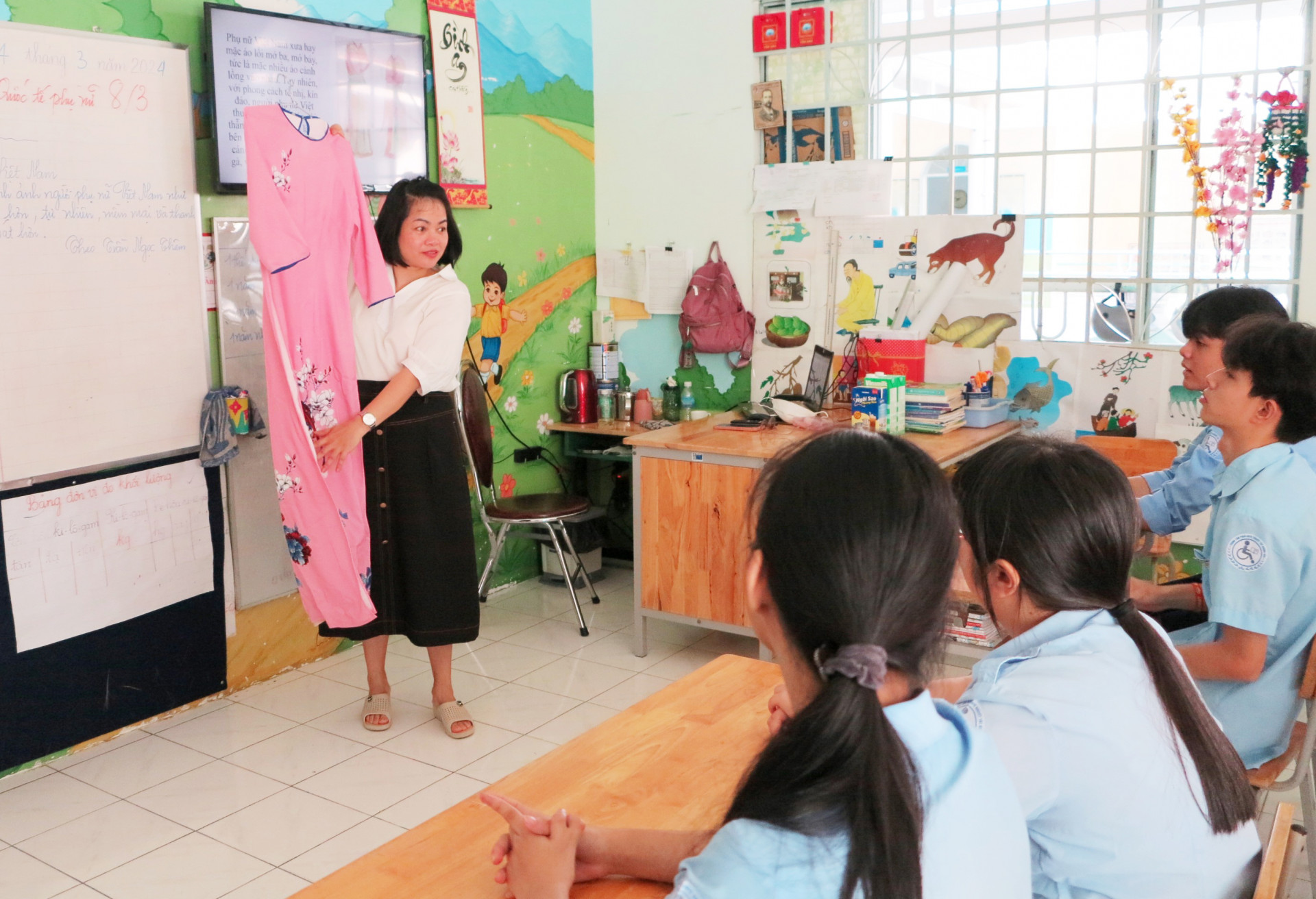 Cô Trần Thị Mỹ Ái giới thiệu với các học sinh về chiếc áo dài Việt Nam.