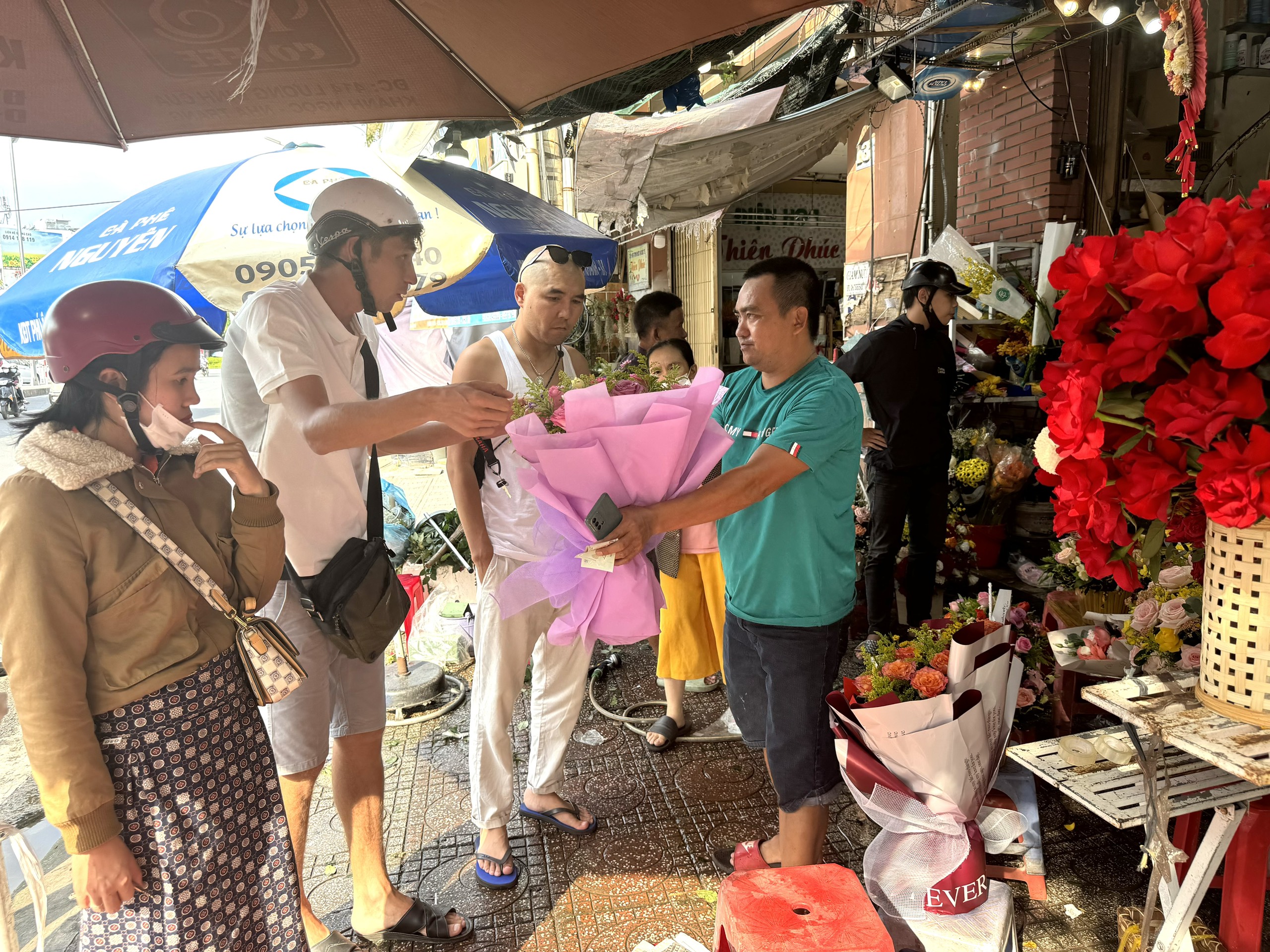 Khách du lịch nước ngoài mua hoa tại một cửa hàng trên đường Nguyễn Trãi