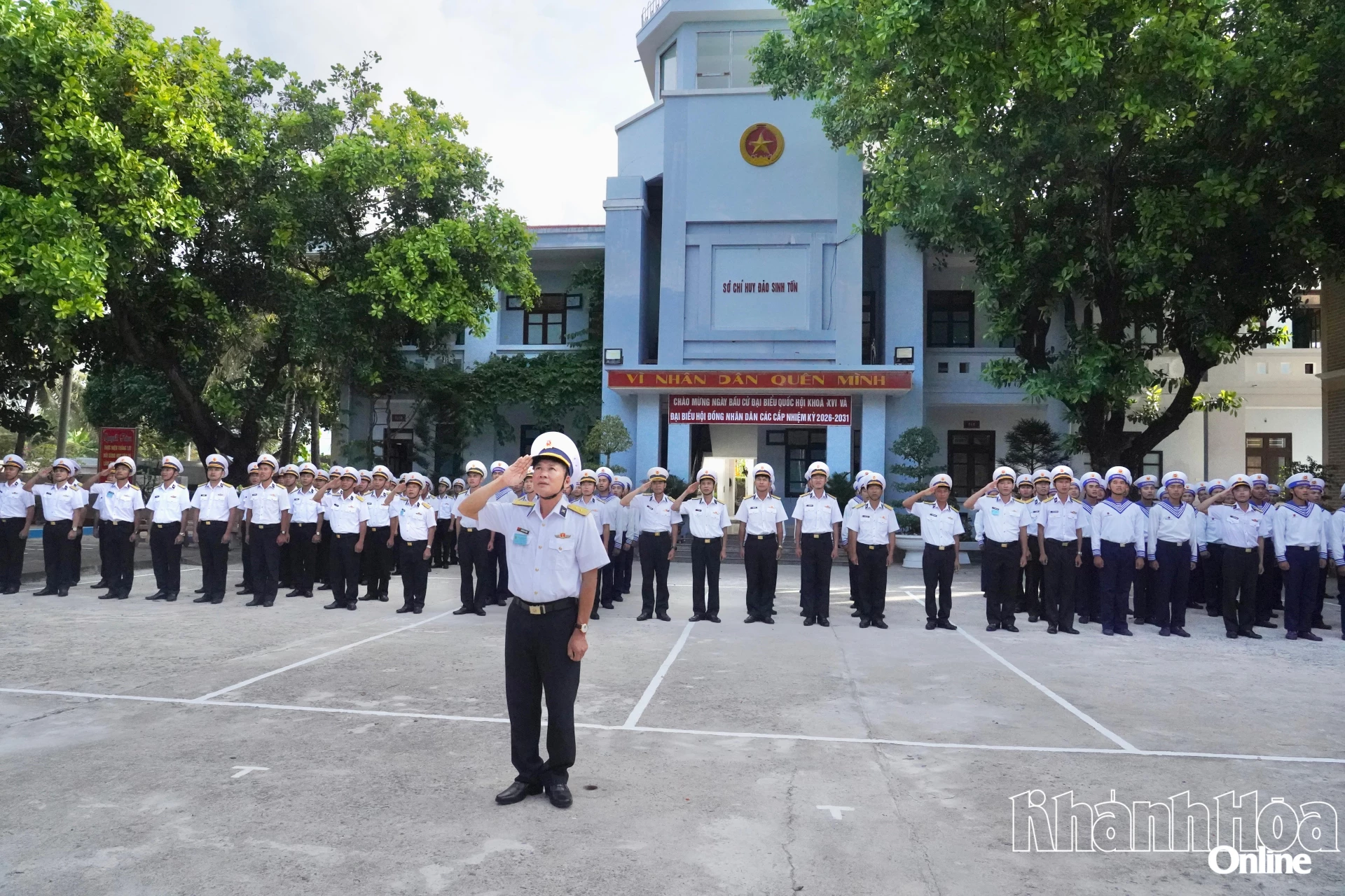 Cán bộ, chiến sĩ và người dân trên đảo Sinh Tồn thực hiện nghi thức chào cờ.