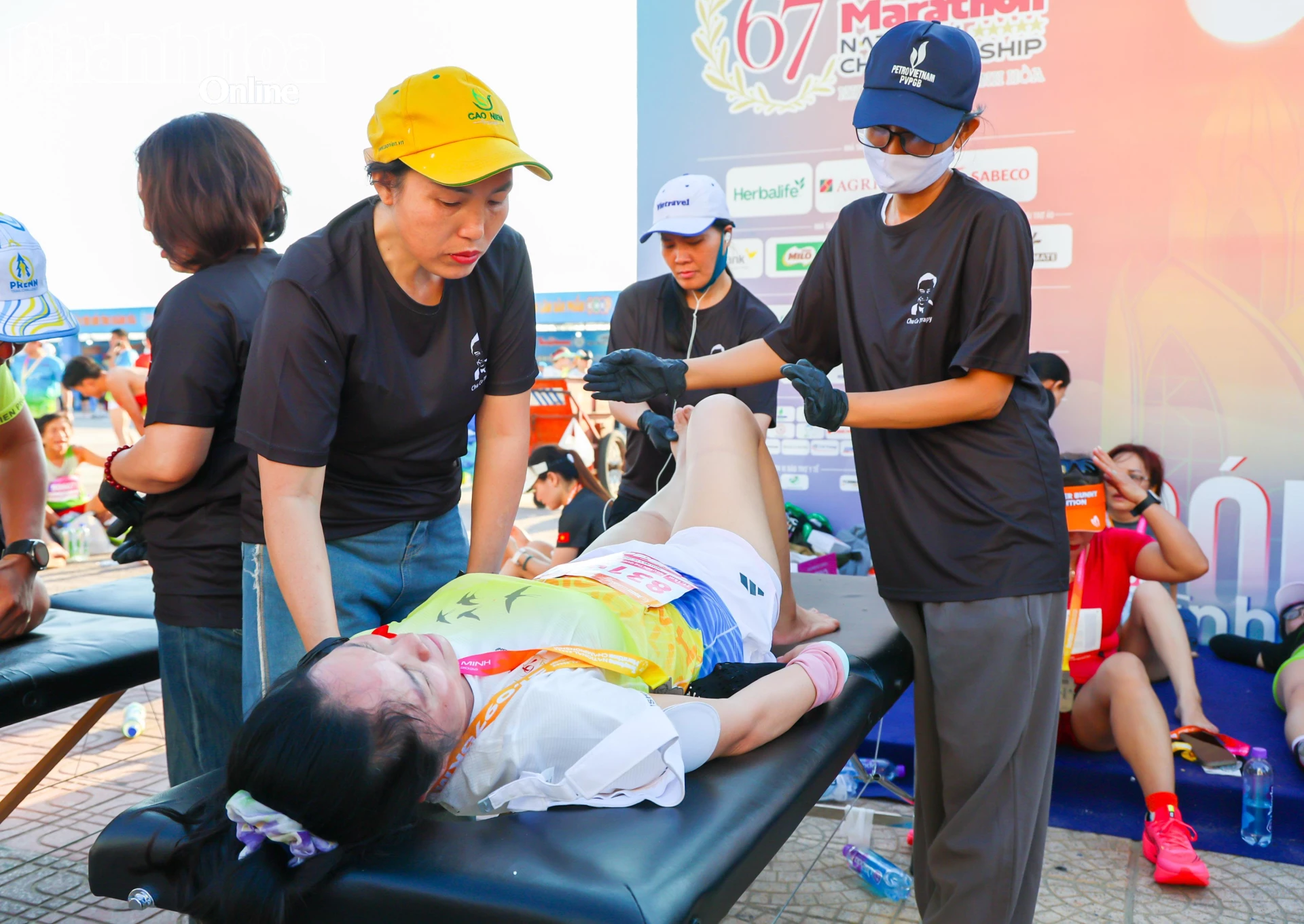Các tình nguyện viên giãn cơ cho vận động viên sau khi về đích.