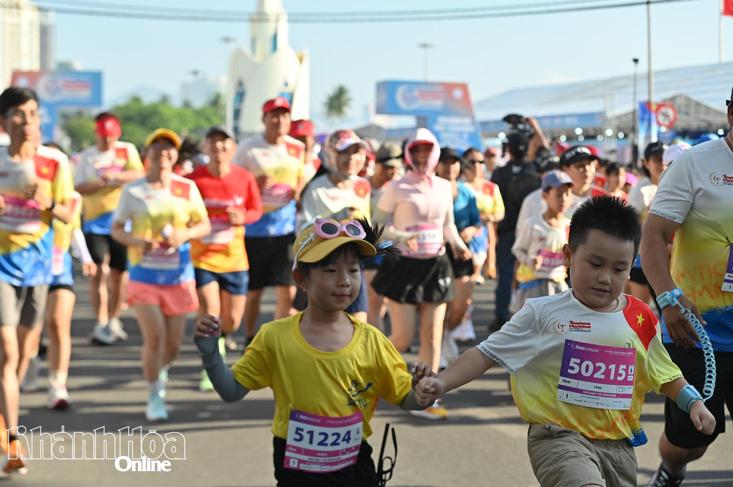 Khoảng khắc hai vận động viên nhí nắm tay nhau trên đường chạy.