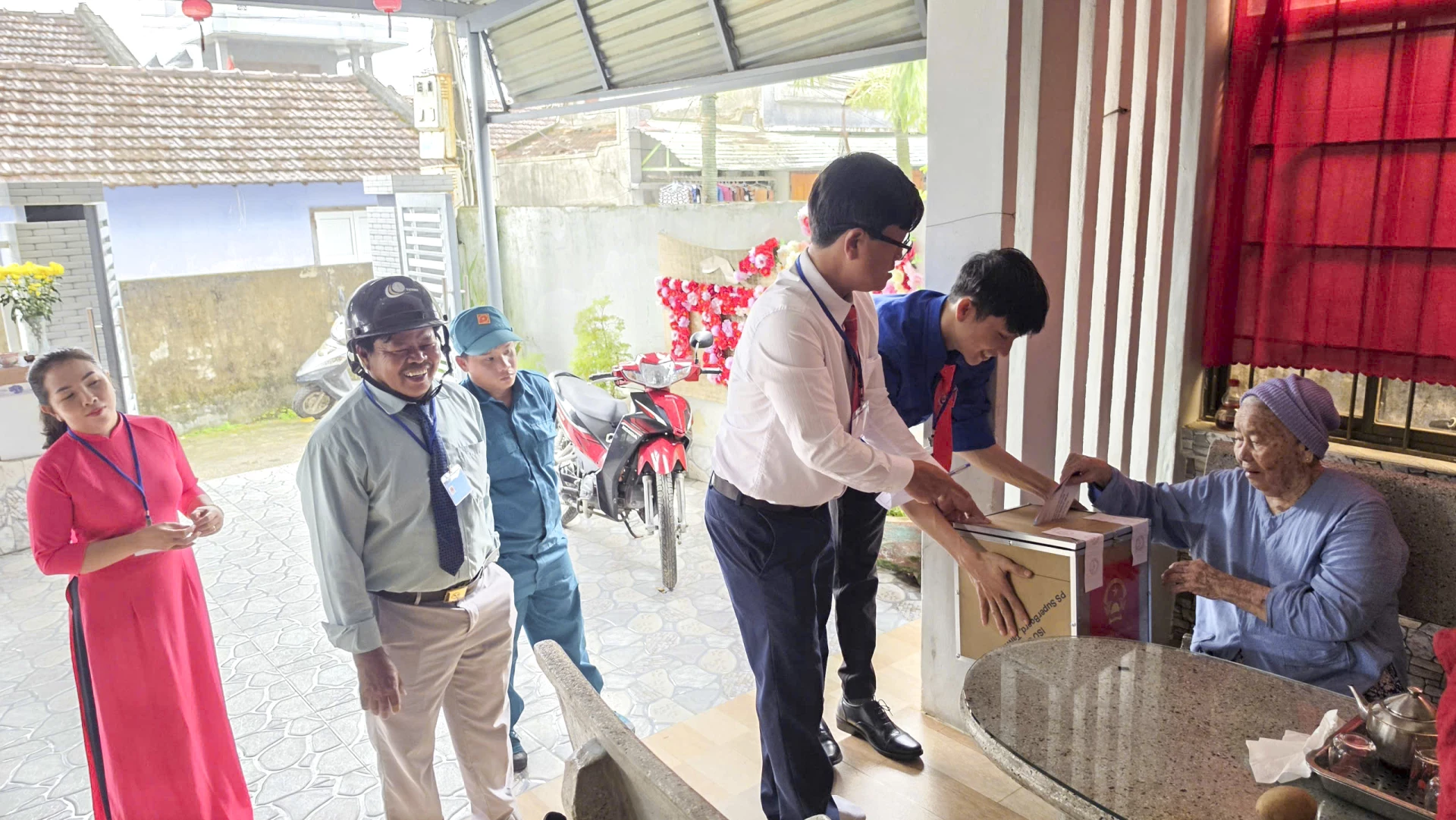 Ông Lê Thanh - Tổ trưởng khu vực bỏ phiếu số 2, cùng Trưởng thôn và các thành viên tổ bầu cử đã trực tiếp mang thùng phiếu đến nhà bà Trần Thị Phán để bà bỏ phiếu. Ảnh: Mạnh Hùng.