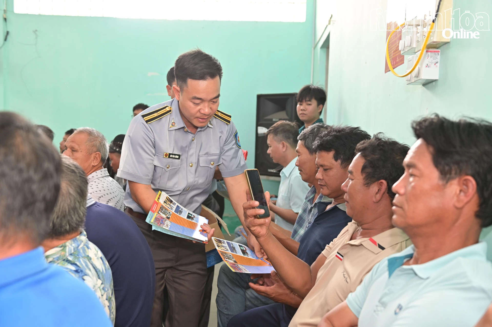 Cán bộ Chi đội Kiểm ngư số 4 phát tờ rơi tuyên truyền cho ngư dân.