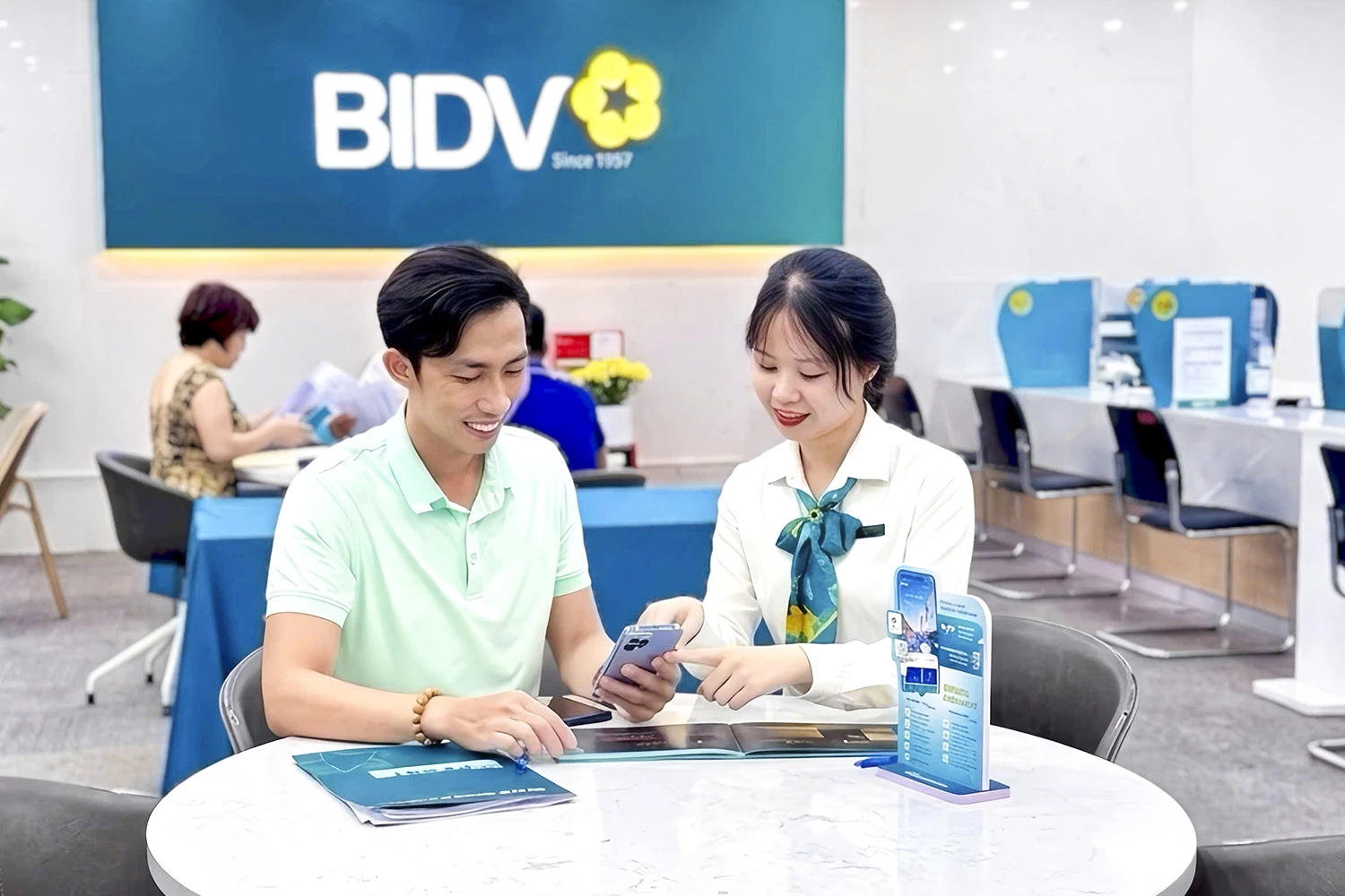 Nhân viên một ngân hàng tư vấn, hỗ trợ cho khách hàng về cách bảo mật đối với ứng dụng Mobile Banking.