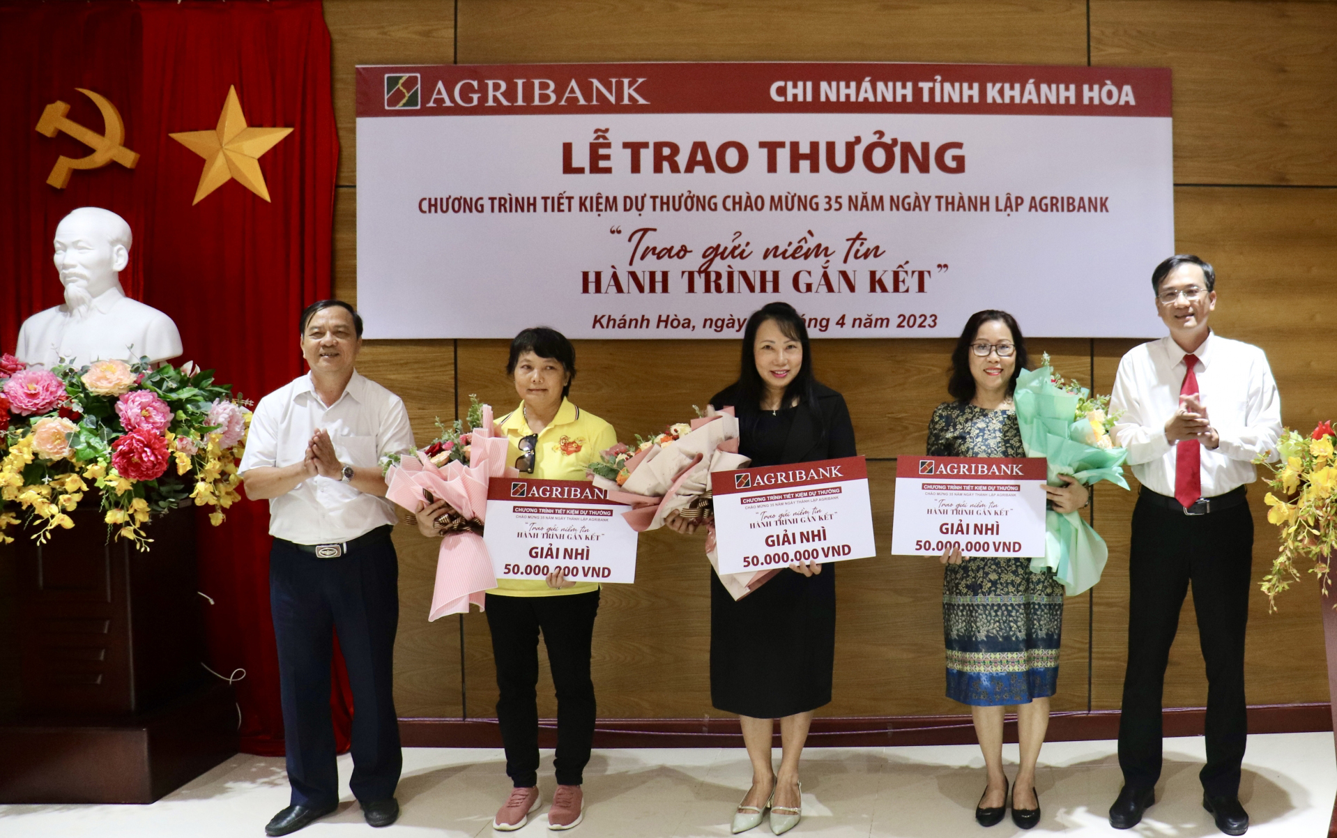 Đại diện Agribank Chi nhánh tỉnh Khánh Hòa tặng hoa chúc mừng và trao bảng tượng trưng giải thưởng cho các khách hàng trúng giải nhì.