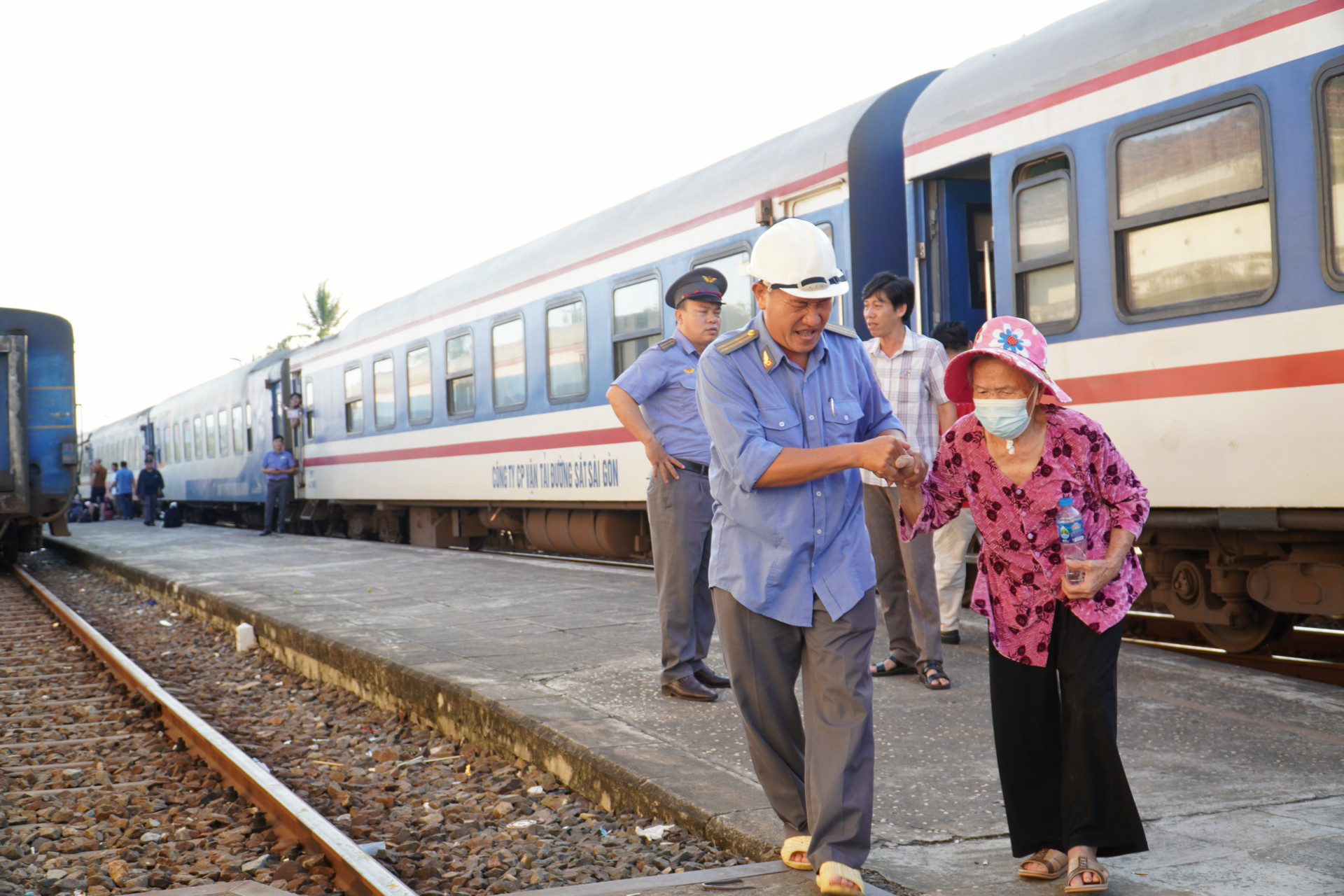 Cán bộ ngành Đường sắt hỗ trợ một người cao tuổi xuống tàu, lên xe để trung chuyển