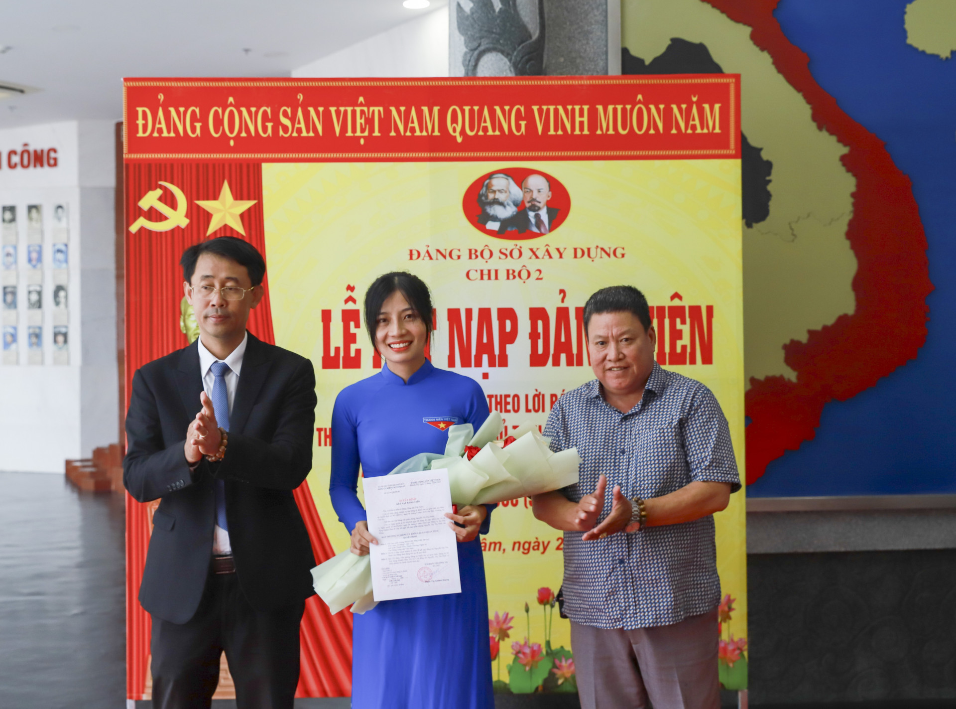 Ông Trịnh Văn Mơ - Phó Bí thư Đảng ủy Khối các cơ quan tỉnh và đại diện Sở Xây dựng trao quyết định, tặng hoa chúc mừng đảng viên mới Nguyễn Thị Thu Hoài.