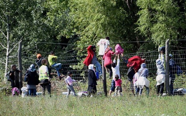 Người di cư vượt qua hàng rào tại khu vực làng Roszke, biên giới Hungary-Serbia. (Ảnh: AFP/TTXVN)

