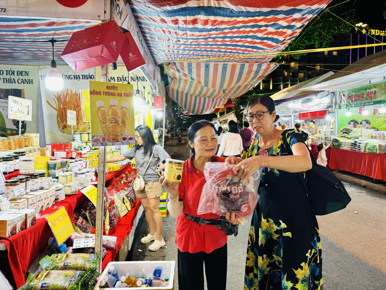 Bà Dương Thị Bé Chín (bìa phải) du khách đến từ Bến Tre tìm hiệu sản phẩm tại phiên chợ