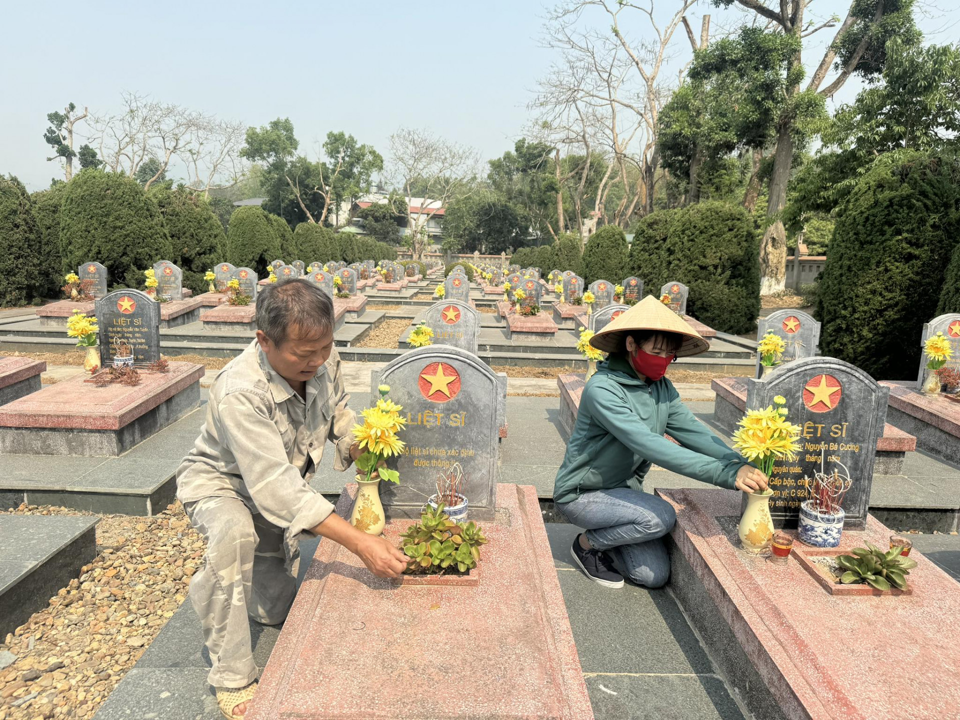 Nhân viên quảng trang chăm sóc mộ liệt sĩ ở Nghĩa trang Đồi Độc Lập.