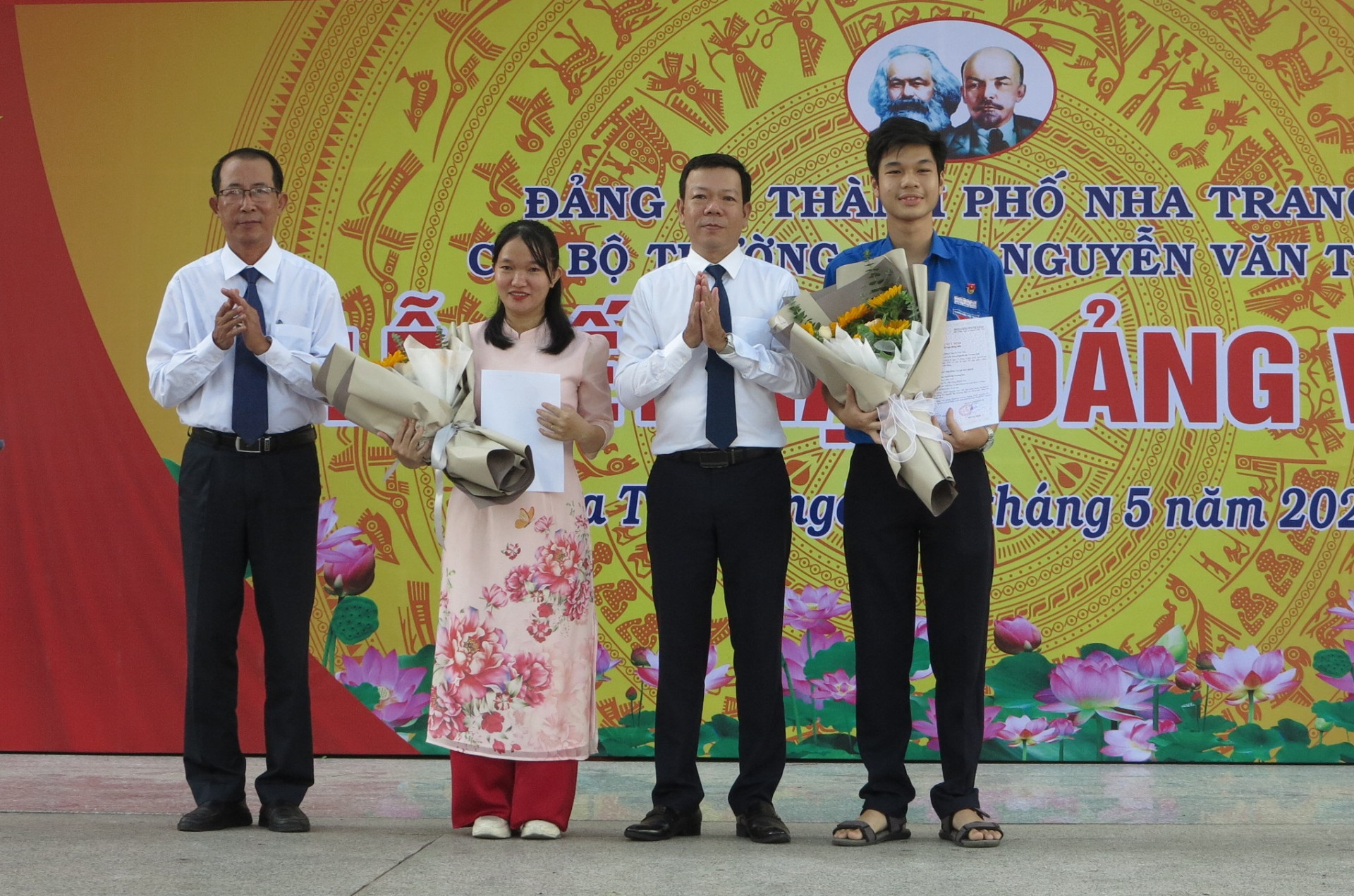 Ông Lê Quang Minh - Phó Trưởng Ban tổ chức Thành ủy Nha Trang (thứ 2 từ phải sang) và thầy Huỳnh Vĩnh Khang tặng hoa chúc mừng 2 đảng viên mới. 