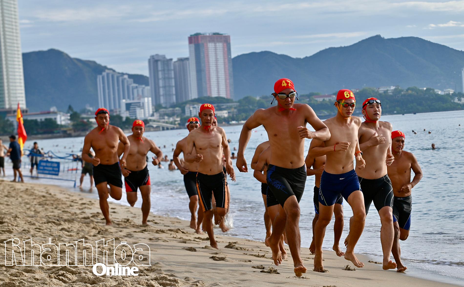 Các vận động viên tranh tài chạy dọc bãi biển trước khi bước vào phần thi bơi tiếp sức.