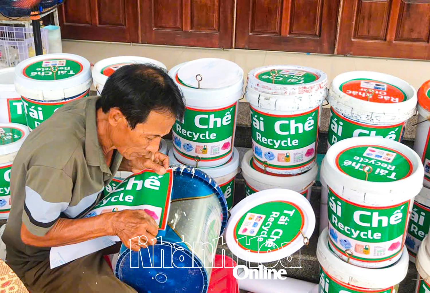 Ông Võ Quốc Trà cẩn thận dán từng chiếc thùng để phát cho người dân dùng phân loại rác thải sinh hoạt.