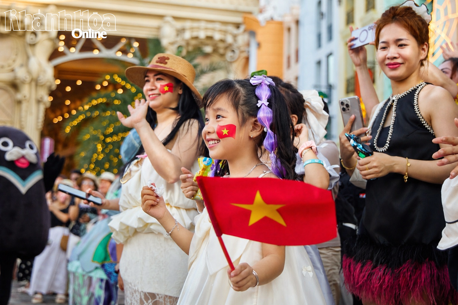 Một em nhỏ cầm lá cờ vẫy theo khi đoàn diễu hành đi qua