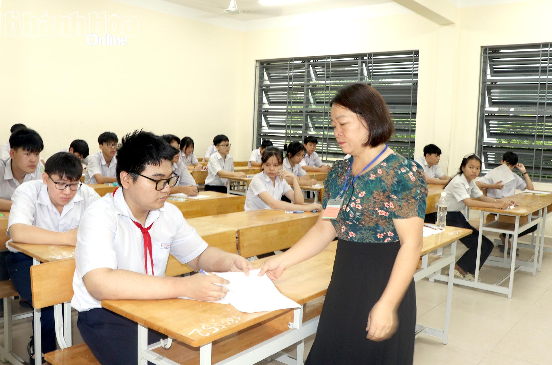 Giám thị phát giấy thi cho thí sinh.