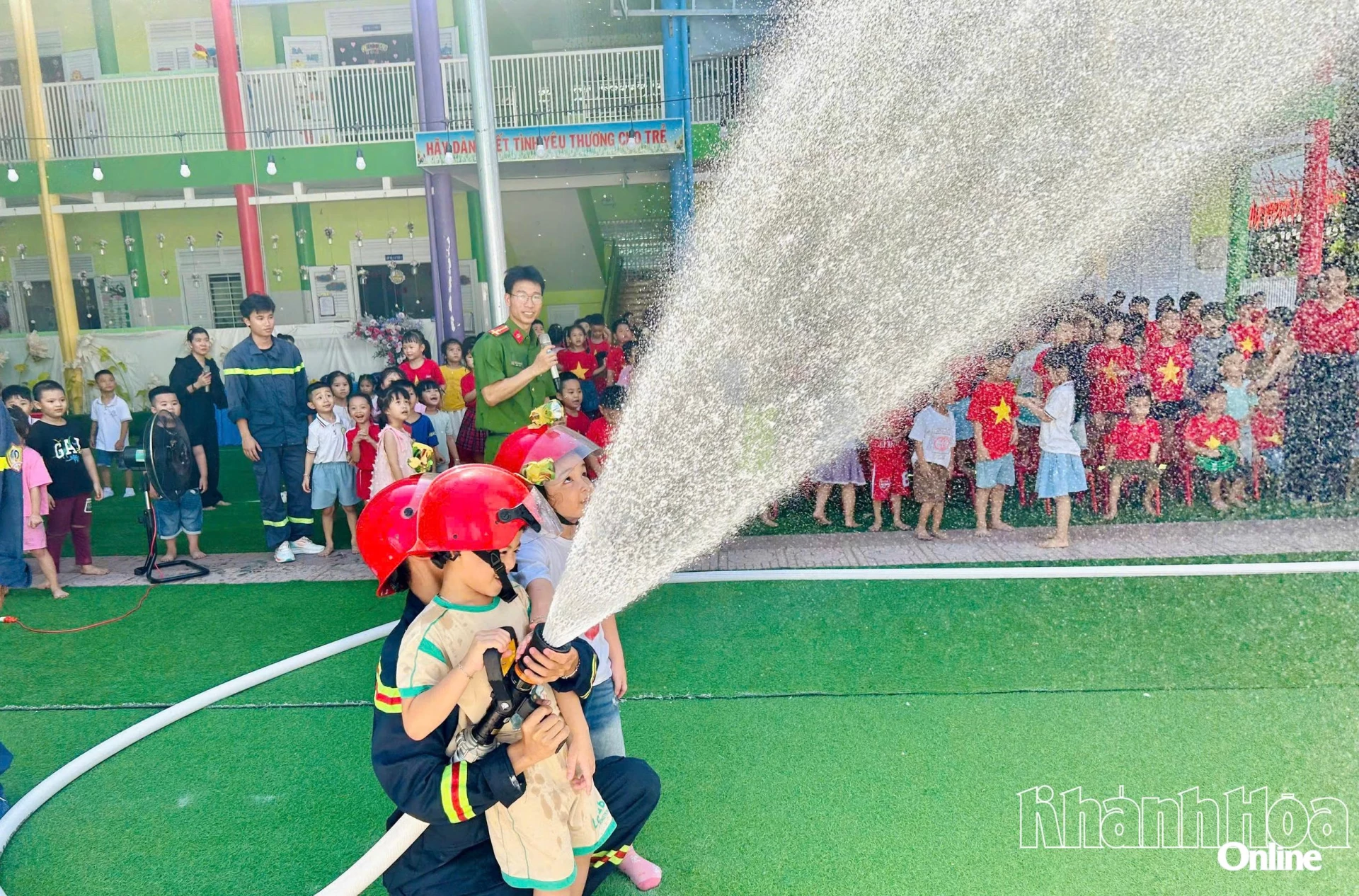 Các chiến sĩ chữa cháy giúp các bé trải nghiệm chữa cháy bằng vòi chữa cháy.