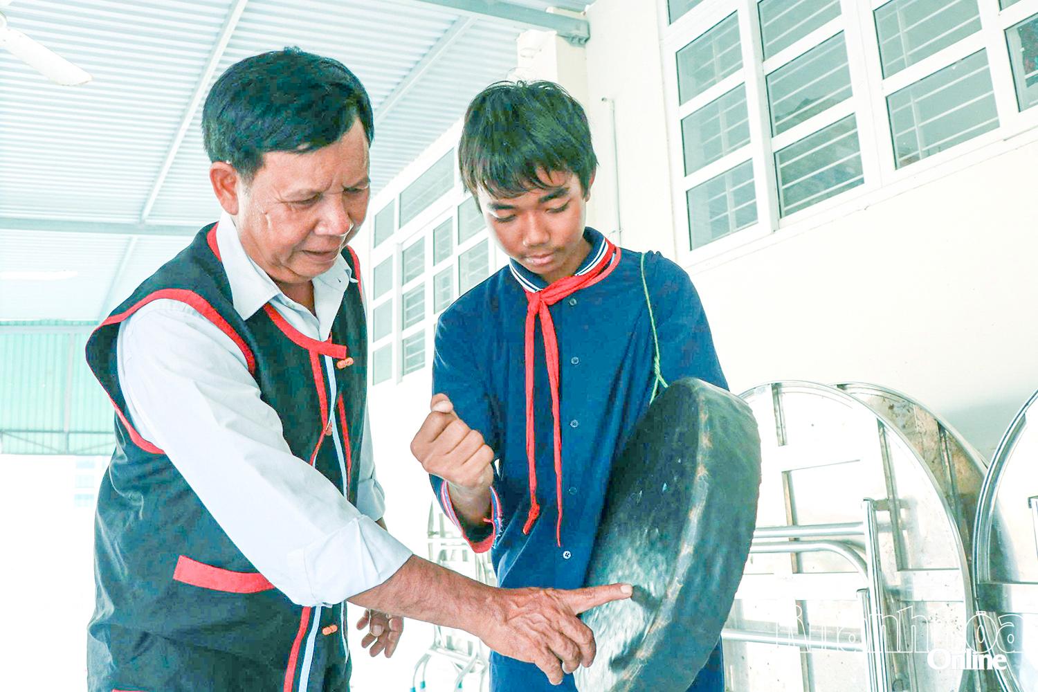 Nghệ nhân Ưu tú Tà Thía Banh tận tình hướng dẫn một học sinh kỹ thuật sử dụng mã la.