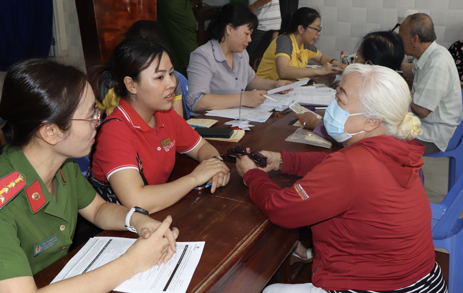 Công an phường Vĩnh Hải và nhân viên bưu điện, ngân hàng tuyên truyền người dân nhận lương hưu, trợ cấp bảo hiểm xã hội hàng tháng qua phương tiện thanh toán không dùng tiền mặt.