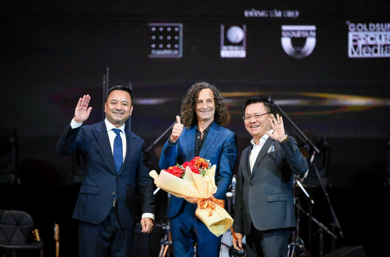 Ông Lê Quốc Minh, Tổng biên tập Báo Nhân Dân (phải); Ông Nguyễn Thùy Dương, Chủ tịch IB Group Việt Nam (trái) cùng Huyền thoại Saxophone Kenny G tại Live concert Kenny G Live in Vietnam - nằm trong dự án âm nhạc quốc tế vì cộng đồng Good Morning Vietnam.