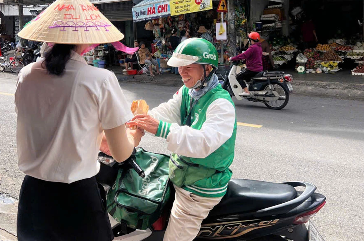 Nhân viên Nhà hàng Cơm Nhà Xanh phát bánh mì miễn phí cho lái xe grab.