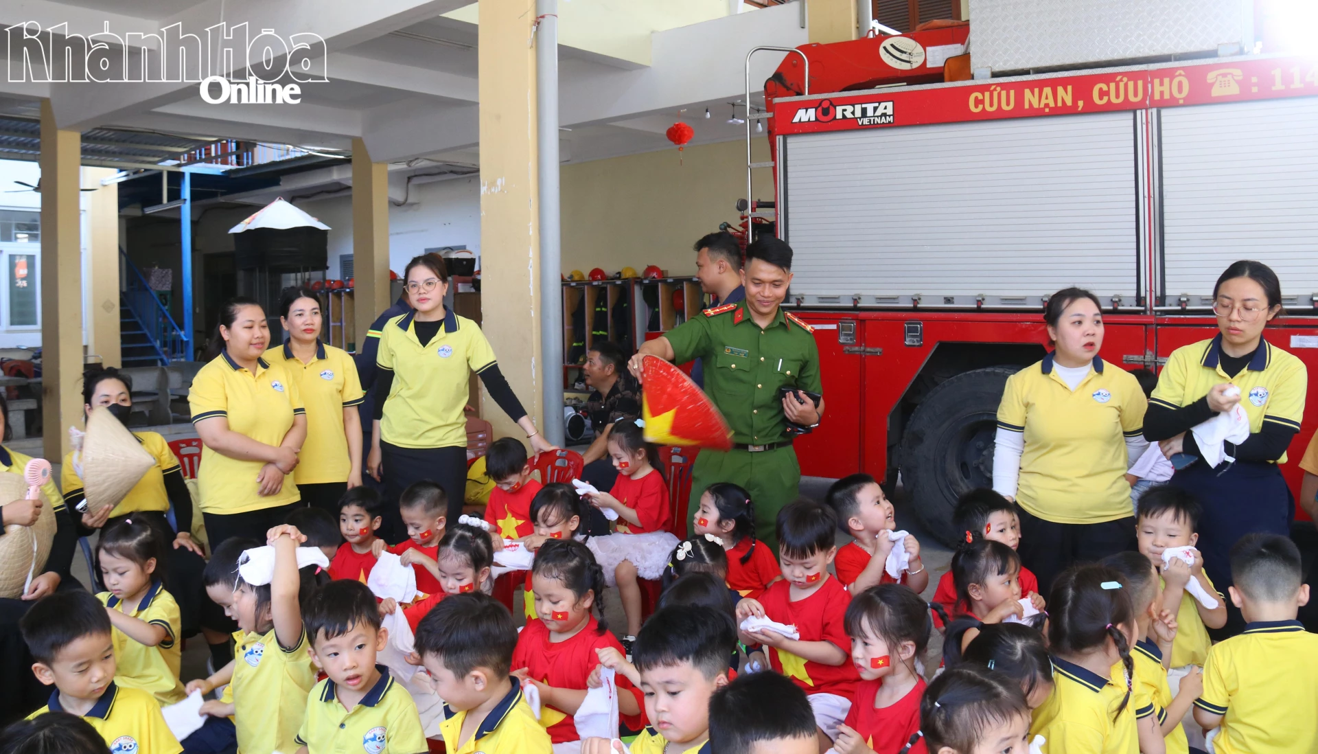 Dưới cái nắng oi của ngày hè, một cán bộ đã sử dụng nón lá quạt mát cho các em nhỏ tham gia chương trình.