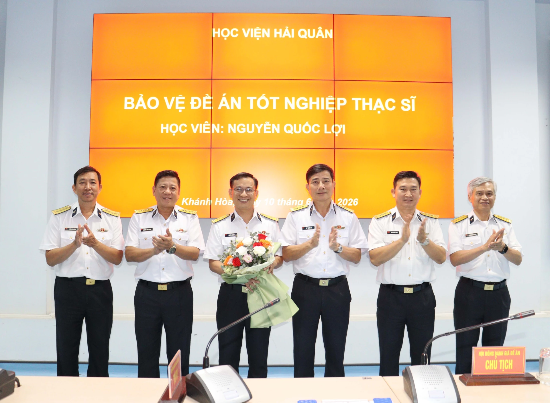 Hội đồng tặng hoa chúc mừng học viên bảo vệ đề án.
