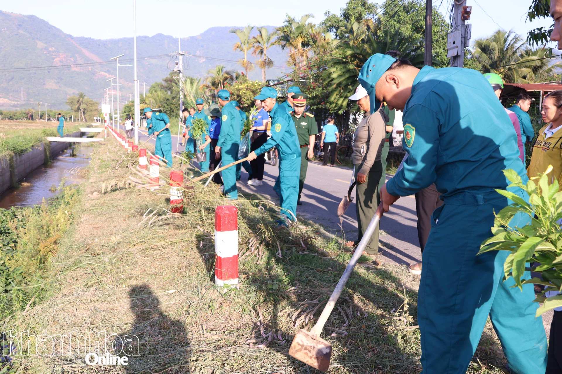 Lực lượng dân quân tự vệ xã Suối Dầu cùng người dân tham gia làm sạch tuyến đường và trồng cây xanh.