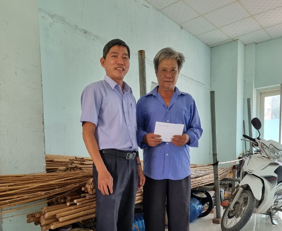 Ông Mai Tấn Hiệp (bìa trái) trao hỗ trợ cho gia đình ông Nguyễn Báu 