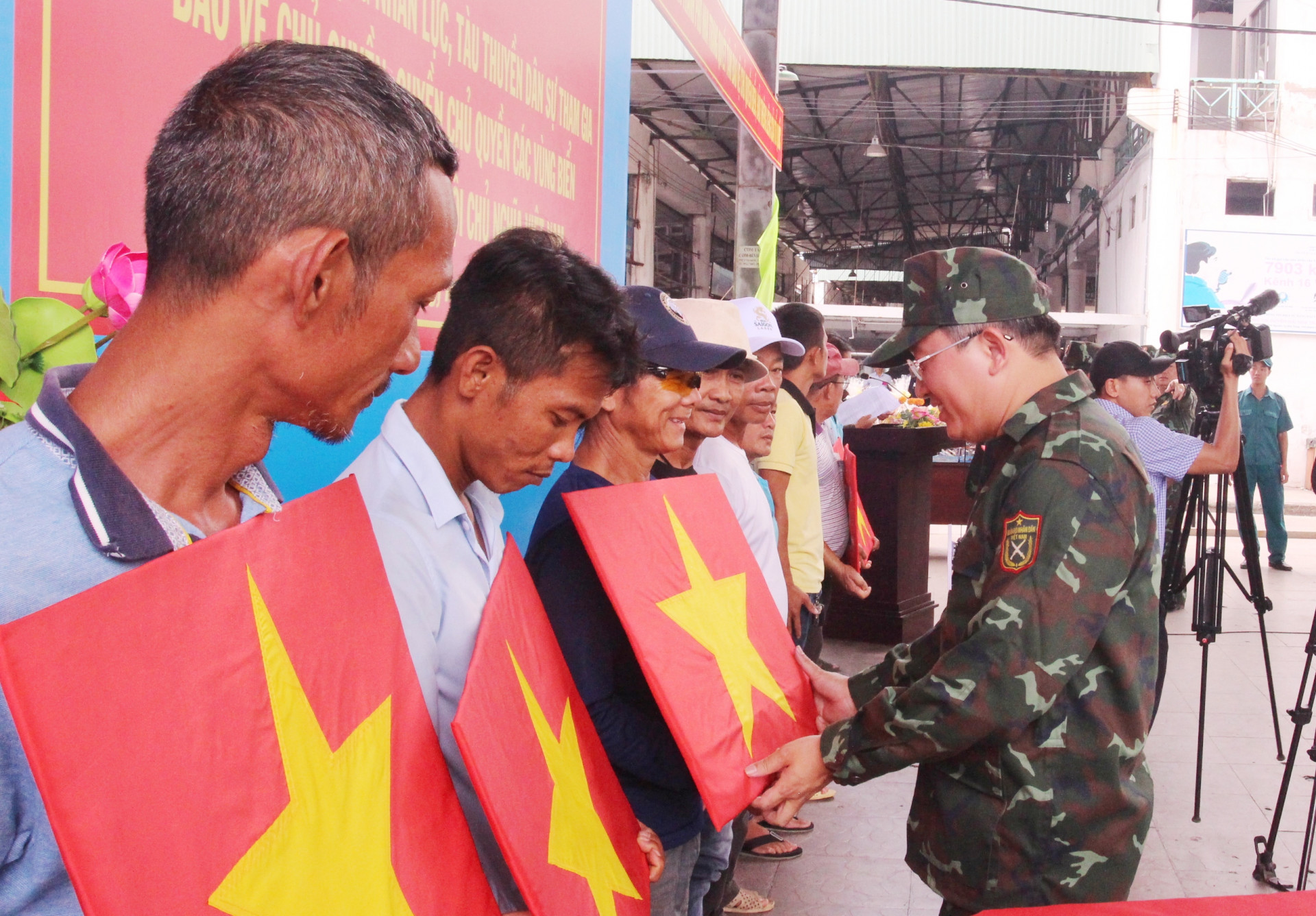 Ông Nguyễn Hải Ninh tặng cờ Tổ quốc cho các ngư dân tham gia diễn tập thực binh.