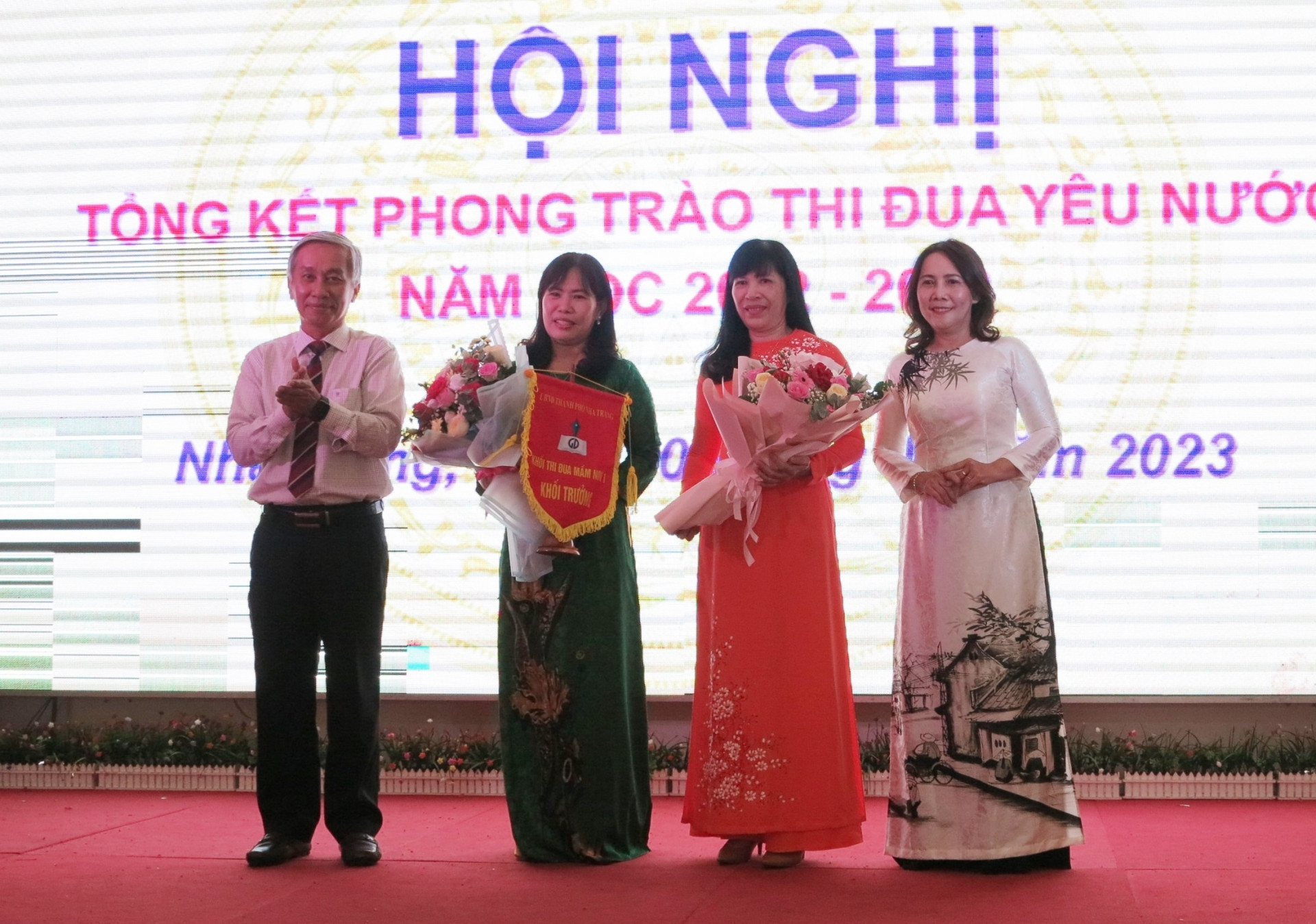 Đại diện Phòng Nội vụ TP. Nha Trang và Hiệu trưởng Trường Mầm non 3-2 tặng cờ và hoa cho Trường Mầm non Vĩnh Trung - đơn vị trưởng khối thi đua và Trường Mầm non Hương Sen - đơn vị phó khối thi đua năm học 2023-2024. 