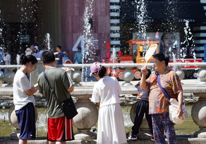 Người dân làm mát tại một đài phun nước trong ngày nắng nóng ở Bắc Kinh (Trung Quốc) ngày 9/6/2024. (Ảnh: THX/TTXVN)